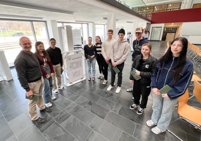 Architekt Peter Laimgruber und Schüler*innen der HLT Saalfelden betrachten gemeinsam die Ausstellung.